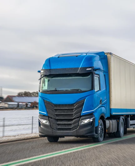 1a574e85-f096-475a-9631-d1d6400fddc7-blue-semi-truck-with-trailer-winter-road-international-freight-transport.jpg